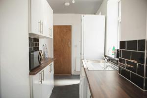 una cucina bianca con lavello e frigorifero di Spaces Central House a Aylestone Altre 5 foto