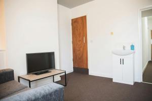 un soggiorno con una TV, un divano e un lavandino di Spaces Central House a Aylestone