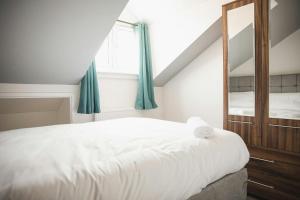 una camera da letto con un letto bianco e uno specchio di Spaces Central House a Aylestone