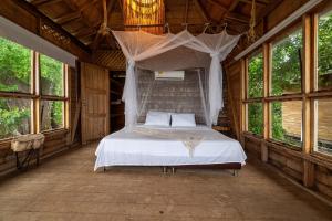 een slaapkamer met een bed in een kamer met ramen bij CasaCoral Hotel in Puerto Limón