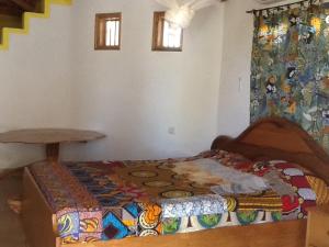 Un dormitorio con una cama con una manta de colores. en Campement Le Cormoran, en Ndangane