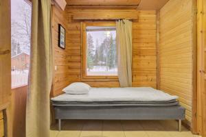 a bed in a wooden room with a window at Pyhäkoti D - 30 Meters From the Slopes in Pyhätunturi