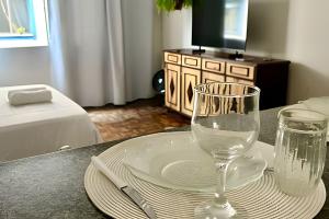 einen Tisch mit einem Teller und einem Weinglas darauf in der Unterkunft Kitnet na rua da UFV com Smart TV e Garagem in Viçosa + 8 Fotos