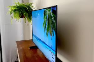 einen Flachbild-TV auf einem Holztisch in der Unterkunft Kitnet na rua da UFV com Smart TV e Garagem in Viçosa