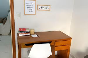 een houten bureau met een witte stoel in een kamer bij No centro com Varanda, Smart Tv, Elevador e Garagem Paga in Viçosa