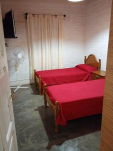 una camera con 2 letti con lenzuola rosse e un ventilatore di Casa Cómoda en Barreal a Barreal