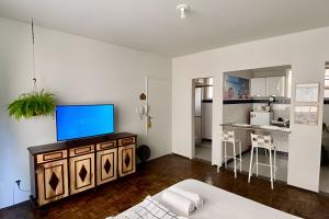 ein Wohnzimmer mit einem TV auf einem Schrank und eine Küche in der Unterkunft Kitnet na rua da UFV com Smart TV e Garagem in Viçosa