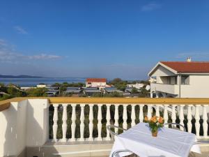 a table with a vase of flowers on a balcony at Pansion Danilo by the sea in Krmčina +26 photos