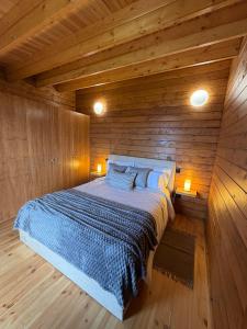 ein Schlafzimmer mit einem Bett in einer Holzwand in der Unterkunft Sunset Eco Shelter 1 in Ponta do Pargo