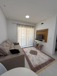 een woonkamer met een bank en een televisie bij Apartamento Elegante 2 Quartos in Balneário Camboriú