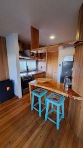 a kitchen with a wooden counter with two stools at Casa Campo Chiloé in Chonchi