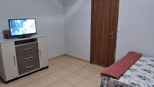 een slaapkamer met een bed en een televisie op een dressoir bij Pousada Central in Montes Claros