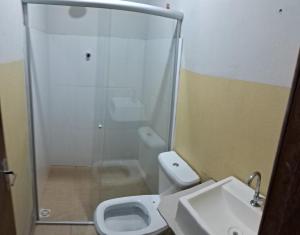 een badkamer met een douche, een toilet en een wastafel bij Pousada Central in Montes Claros