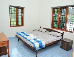 a bedroom with a bed with a table and windows at White Haven in Angamaly