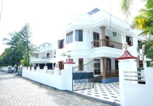 a white building with a fence in front of it at White Haven in Angamaly