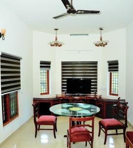 a living room with a table and chairs and a tv at White Haven in Angamaly
