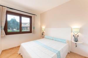 een witte slaapkamer met een bed en een raam bij Comfy studio with pool in Vignola Mare