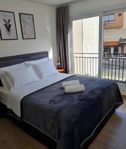 a bedroom with a large bed with a large window at Apartamento Loft Gramado in Gramado