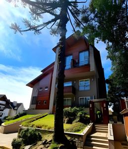a building with a tree in front of it at Apartamento Loft Gramado in Gramado