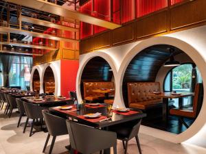 a dining room with tables and chairs and red walls at ibis Dubai One Central in Dubai