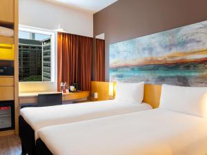 ein Hotelzimmer mit 2 Betten und einem Gemälde in der Unterkunft ibis Dubai One Central in Dubai