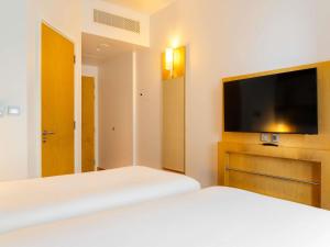 ein Schlafzimmer mit zwei Betten und einem Flachbildfernseher in der Unterkunft ibis Dubai One Central in Dubai + 126 Fotos
