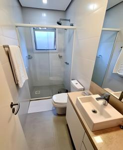 a bathroom with a shower and a toilet and a sink at Apartamento Loft Gramado in Gramado