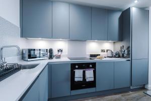 een keuken met blauwe kasten en een magnetron bij City View Apartment with Pool in Manchester