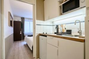 een keuken met witte kasten, een wastafel en een bed bij Studio Vauban, Lille in Lille