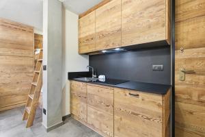 een keuken met houten kasten en een spoelbak bij Hostdomus-Mountain Nest in Sauze d'Oulx