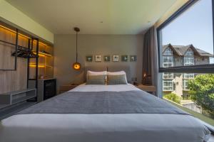 a bedroom with a large bed and a large window at Laghetto Stilo Garden in Gramado +47 photos