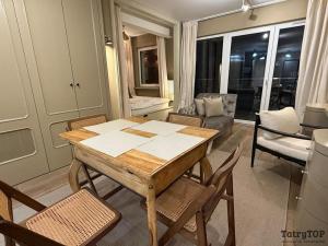 einen Holztisch und Stühle im Wohnzimmer in der Unterkunft TatryTop Apartament Szałwiowy in Nowy Targ + 3 Fotos