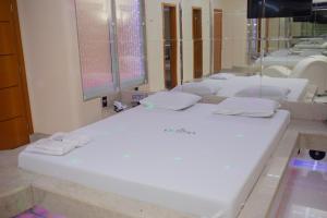 a bathroom with a large white bed in front of a mirror at Pousada Olimpo in Ananindeua