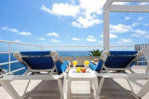 two chairs and a table on a balcony with the ocean at Bahia Blanca in Puerto Rico de Gran Canaria