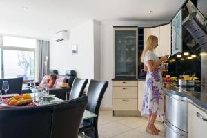 a woman standing in a kitchen looking at her cell phone at Bahia Blanca in Puerto Rico de Gran Canaria +27 photos