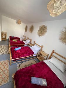 three beds in a room with red blankets and pillows at Atlantic refuge in Wassane