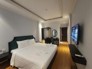 a bedroom with a large bed and a flat screen tv at Maya Central Hotel & Spa in Hanoi