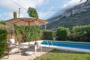 a patio with a table and an umbrella next to a pool at Casa MaJa in Denia