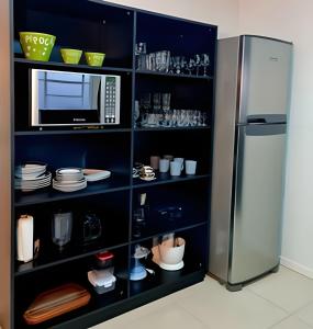 a kitchen with a microwave and a refrigerator at Apartamento Major Nicoletti in Gramado