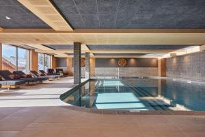 a swimming pool in a hotel with couches at Résidence Odalys L'Ecrin Blanc in La Rosière