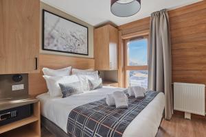 a bedroom with a large bed with a window at Résidence Odalys L'Ecrin Blanc in La Rosière +202 photos