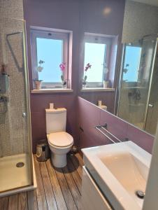a bathroom with a toilet and a sink and two windows at Beach Hub in São Martinho do Porto