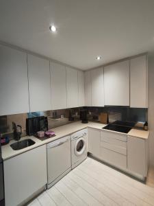 a kitchen with white cabinets and a washing machine at Beach Hub in São Martinho do Porto