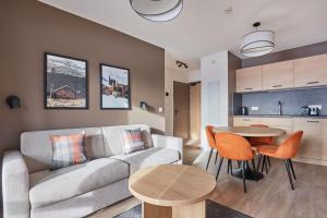 a living room with a couch and a table at Résidence Odalys L'Ecrin Blanc in La Rosière