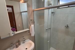 a bathroom with a glass shower and a sink at Classe A in Viçosa