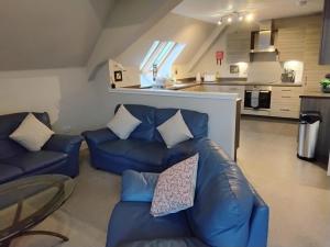 uma sala de estar com dois sofás azuis e uma cozinha em Turfhill House em New Deer