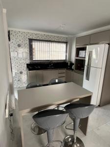 una cucina con bancone, sgabelli e frigorifero di Aurora Boreal a Tijucas