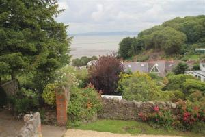 a garden with a stone wall and a view of the ocean at 2 Bed in Mumbles oc-hh133 in The Mumbles
