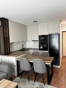 eine Küche mit weißen Schränken und einem Holztisch mit Stühlen in der Unterkunft Apartment Viewpoint in Posušje