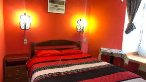 een slaapkamer met oranje muren en een bed met rode kussens bij Casa María Victoria 